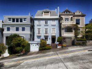 a row of townhomes in san francisco that are on a steep hill 