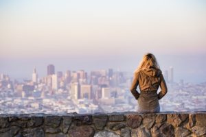 girl sitting on brick wall overlooking san francisco skyline.